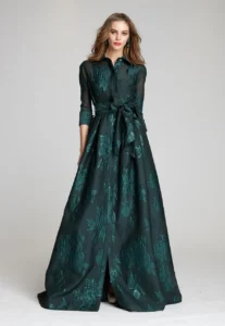 Dress shown in emerald and also available in champagne, navy, navy multi, powder blue and blush. This elegant three-quarter sleeve shirt waist gown, crafted from metallic jacquard, featuring a timeless style features a classic a shirt-dress inspired silhouette that combines an A-line graceful skirt, button cuffs, a self-tie bow at the waist and a full skirt. A collared neckline and concealed button-down front add tailored refinement, while the three-quarter sleeves with cuffed detail provide polished coverage. The gown is finished with a removable self-tie sash belt that defines the waist and enhances the flattering A-line skirt.