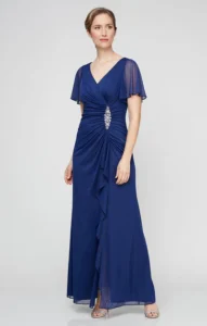 Dress shown in electric blue. This stunning mesh dress features a long surplice neckline and flutter sleeves, creating an elegant and flattering silhouette. With intricate embellishments at the hip and a cascading skirt detail, this dress is perfect for any special occasion. You'll feel confident and beautiful in this expertly crafted dress.